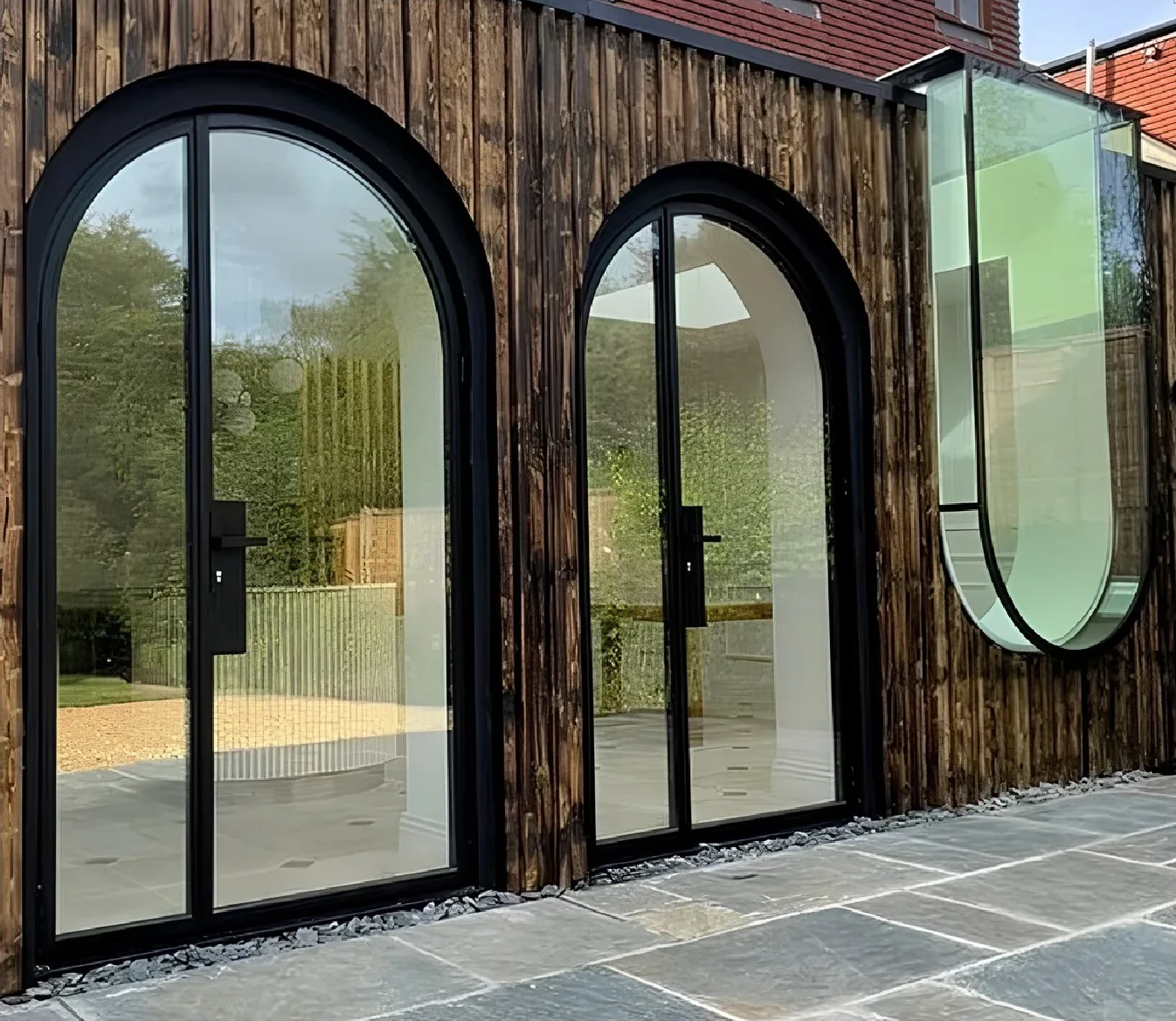 Arched steel doors on a timber-clad facade